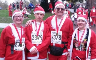 Family of four dressed as Santas wearing medals